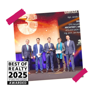 Skupina lidí v oblecích na pódiu s oceněním Best of Realty před velkým displejem.