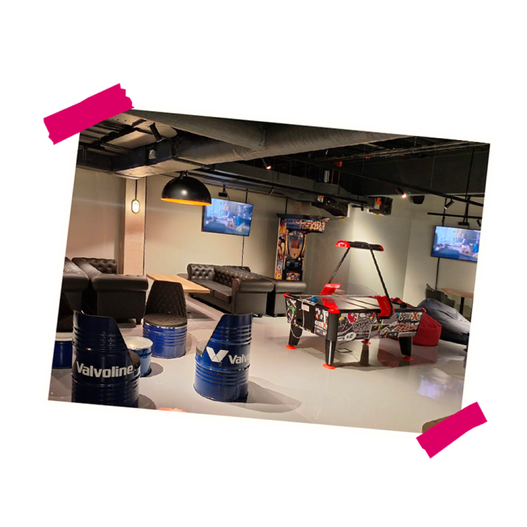 Interiér nového relaxačního prostoru V LOUNGE s pohodlnými pohovkami, herními automaty a obrazovkami na stěnách.