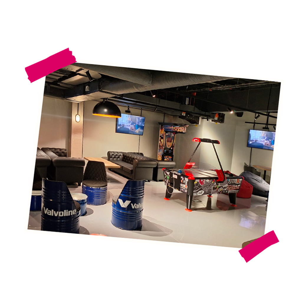 Interiér nového relaxačního prostoru V LOUNGE s pohodlnými pohovkami, herními automaty a obrazovkami na stěnách.