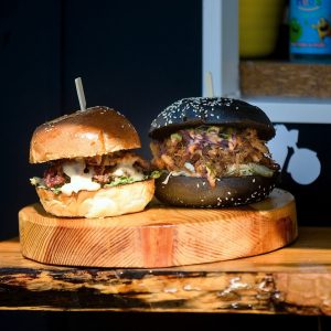 Dva různé hamburgery na dřevěném prkénku