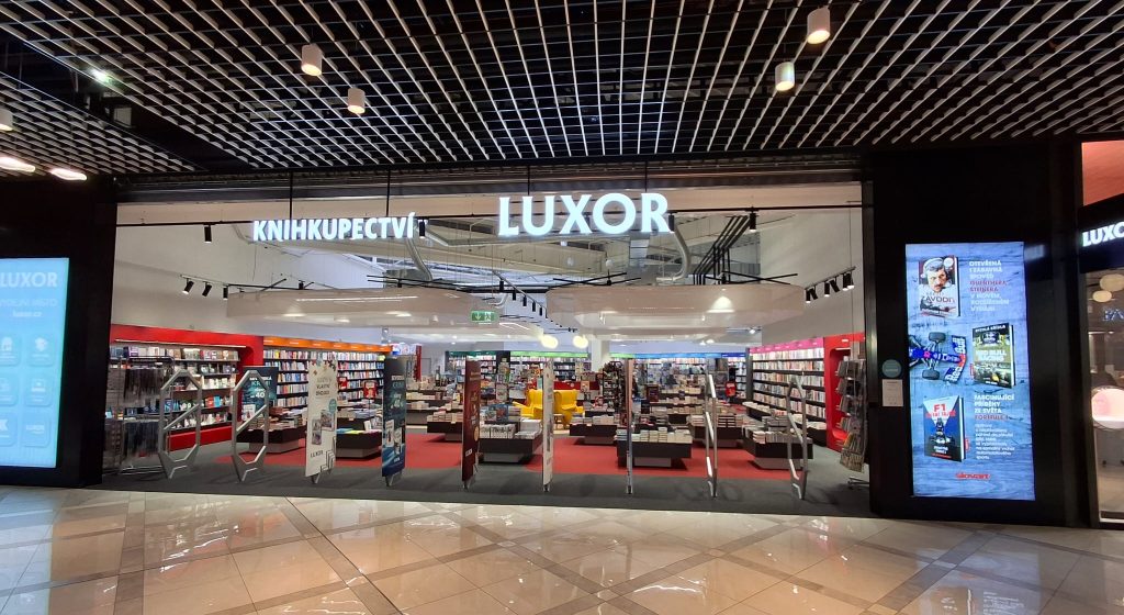 ALT text: Vstup do knihkupectví Luxor s viditelnými knihami na regálech