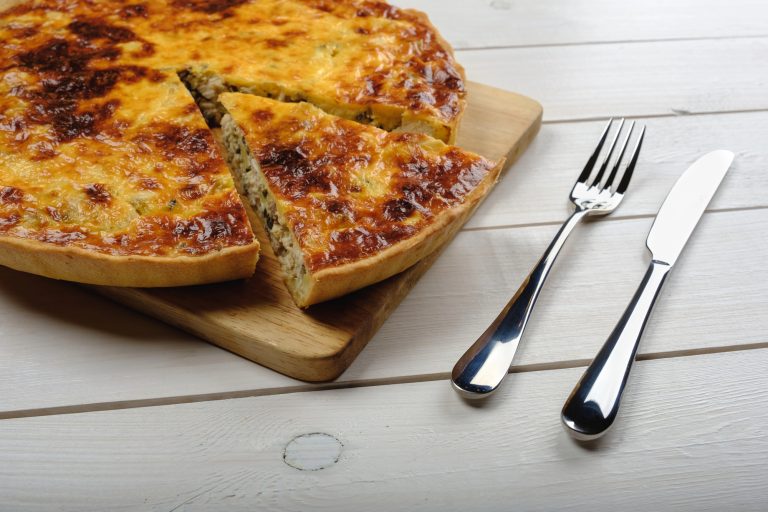 Slaný quiche na prkénku s příborem vedle