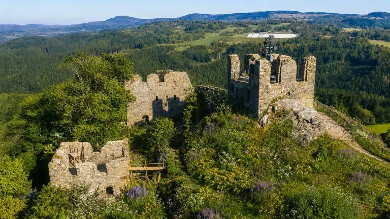 Zřícenina hradu na vrcholu kopce obklopená lesy