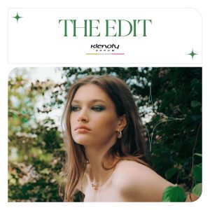 Žena s dlouhými vlasy pózuje v přírodním prostředí, nosí elegantní šperky z kolekce The Edit od Klenot Aurum.